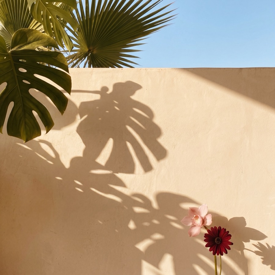 Palm leaves and blooms against a warm wall